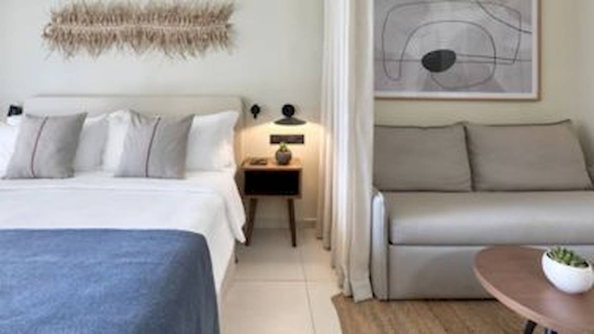 Hotelzimmer im Domes Aulus Zante mit einem Bett, einem Nachttisch und einem Sofa.