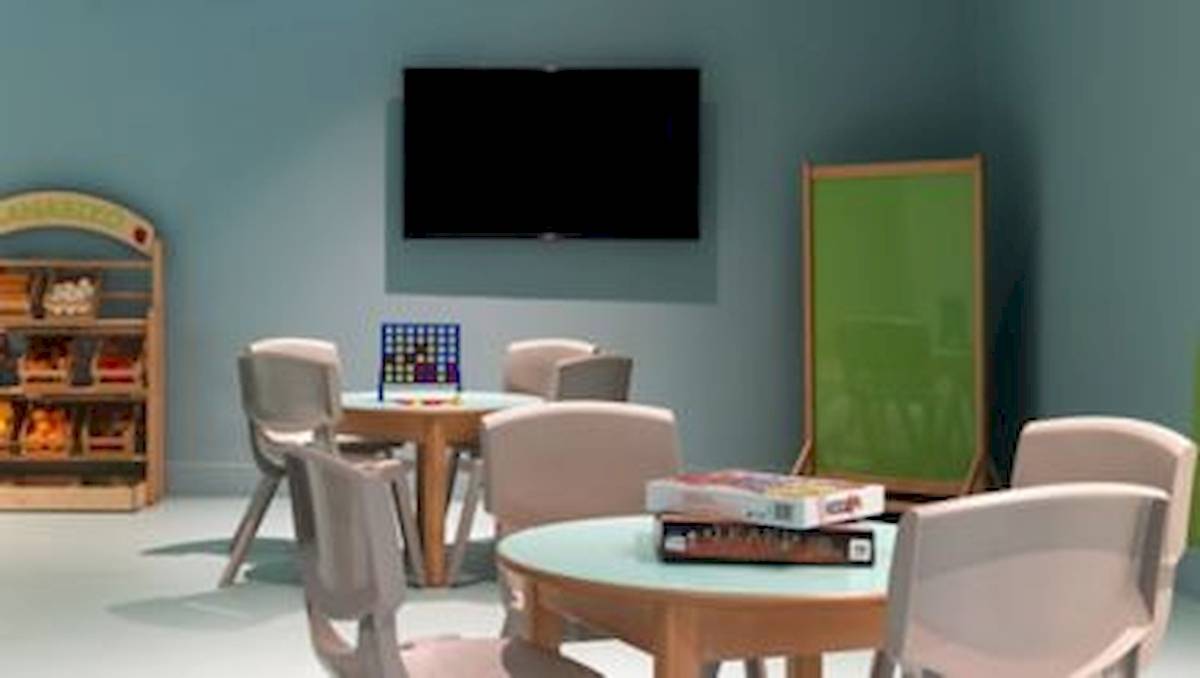Spielzimmer im Domes Aulus Zante Hotel mit Tisch, Stühlen, Büchern und Fernseher.