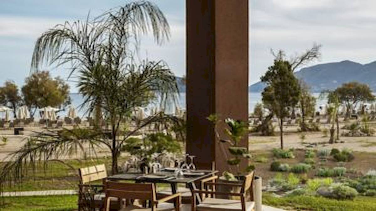 Außenbereich des Domes Aulus Zante Hotels mit Tisch und Blick auf das Meer.