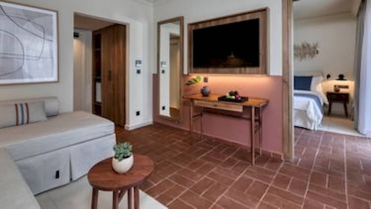 Suitenzimmer im Domes Aulus Zante mit Fernseher, Tisch, Sofa und Schlafzimmer.