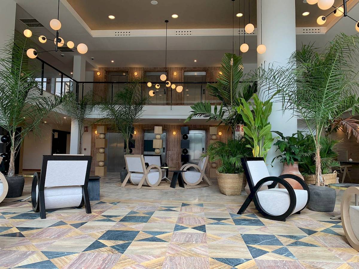 Lobby des H10 Costa Mogan Hotels mit moderner Einrichtung und vielen Pflanzen.
