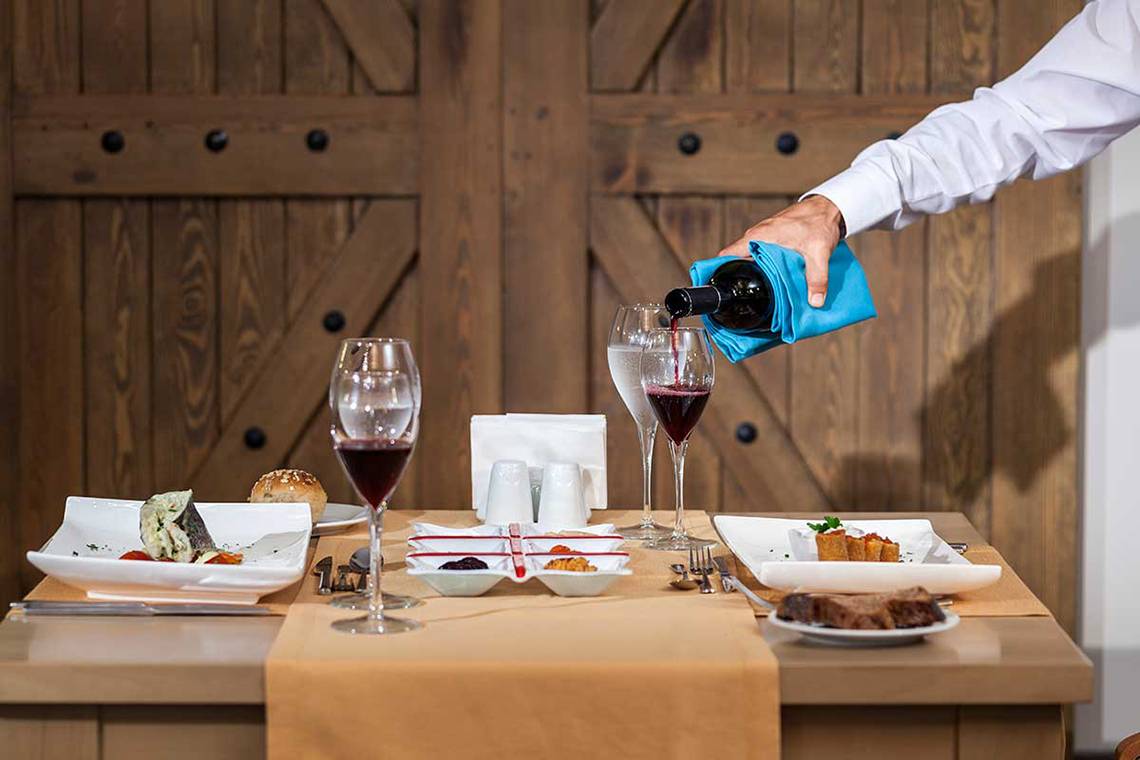 Ein Tisch mit Speisen und Getränken, darunter Wein und Wasser in Gläsern.