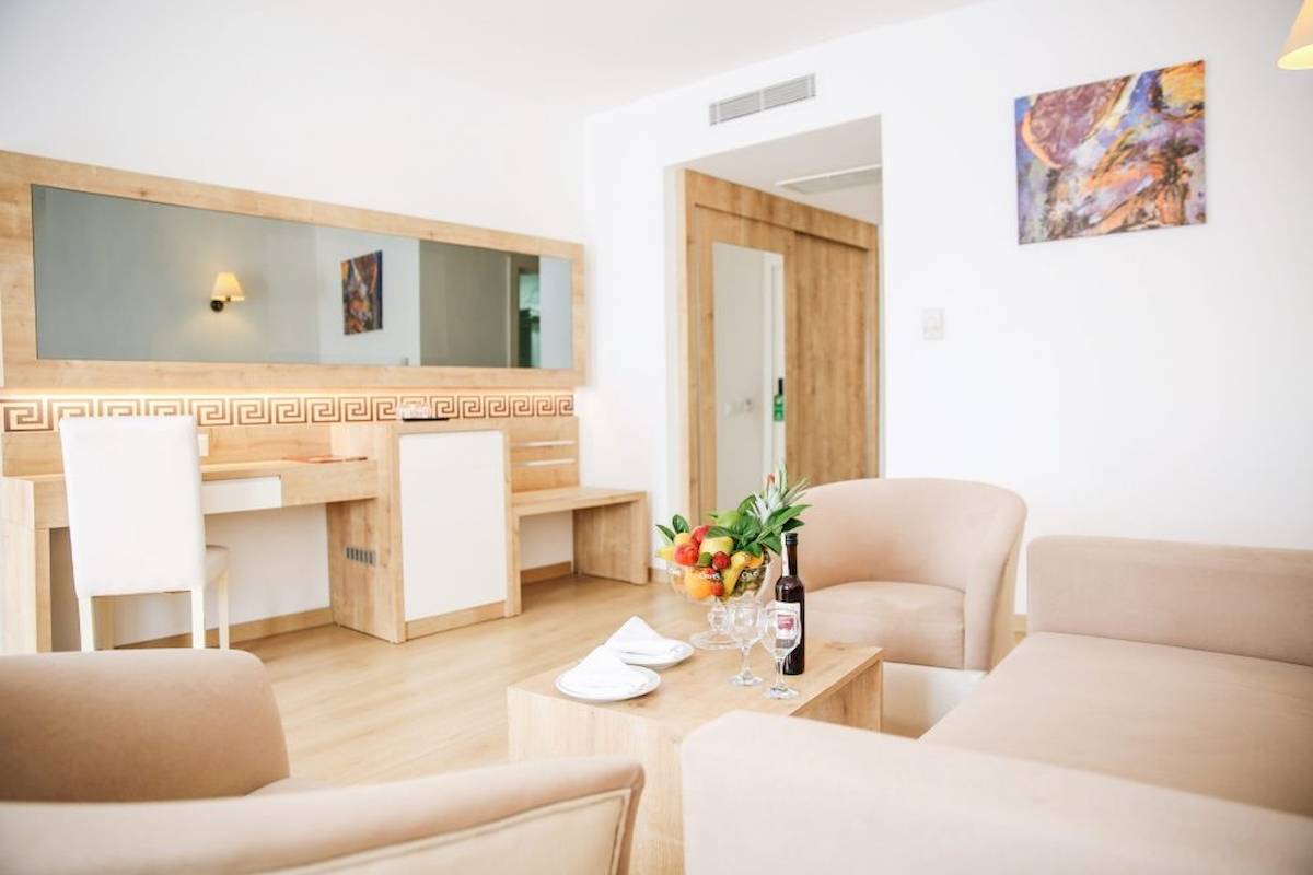 Suite-Zimmer im Cesars Side Hotel mit modernem Interieur, Couch, Tisch, Früchten und Wein.