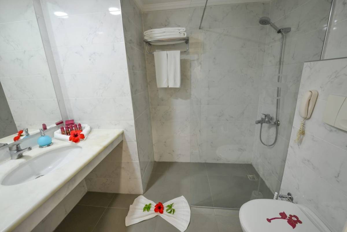 Badezimmer im Cesars Side Hotel mit Dusche, Waschbecken und Toilette.