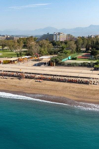 Luftaufnahme des Megasaray Resort Side Strand mit Liegen und Gebäuden im Hintergrund.