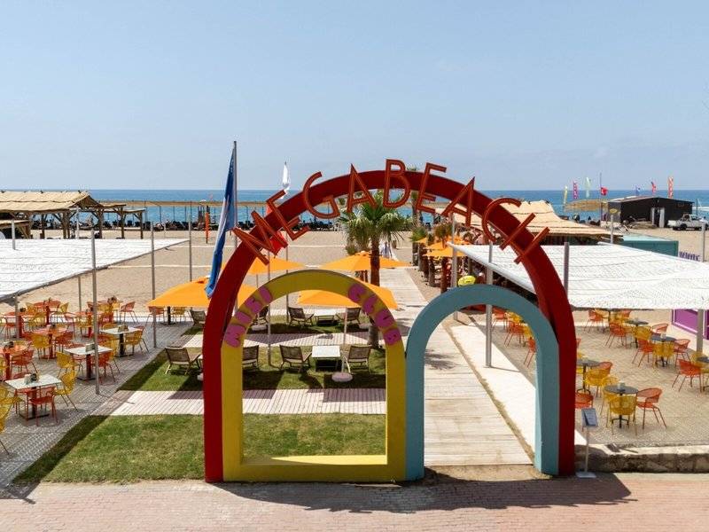 Außenbereich des Megasaray Resort Side mit bunten Eingangsbogen und Strandliegen