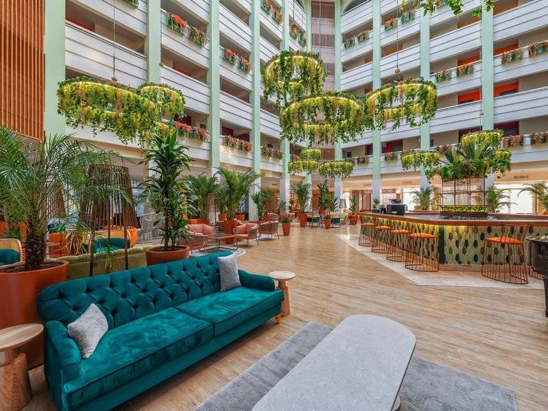 Innenansicht der Lobby im Megasaray Resort Side mit grünen Sofas, Pflanzen und einer Bar.