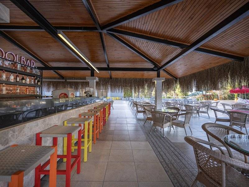Innenansicht der Bar des Megasaray Resort Side mit Thekenhockern, Tischen und Stühlen.