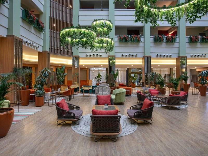 Lobby des Megasaray Resort Side mit runden Tischen, Stühlen und Pflanzen.
