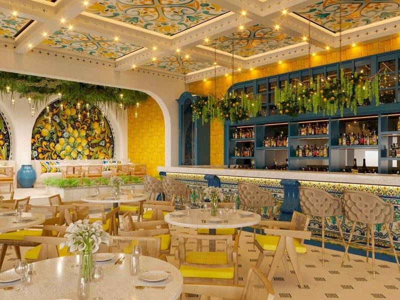 Inneneinrichtung des Sheraton Doha Resort Convention Hotel mit gelben und blauen Dekor, Tischen, Stühlen und einer Bar.