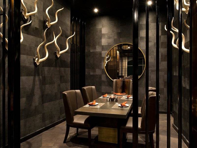 Restauranttisch im Marsa Malaz Kempinski Hotel mit dekorierten Wänden und runden Spiegel.
