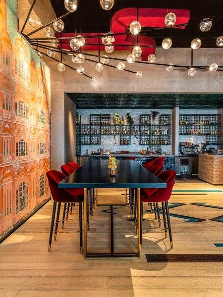 Innenbereich des Rixos Gulf Hotel Doha mit rotem Stuhlkreis und Bar im Hintergrund.