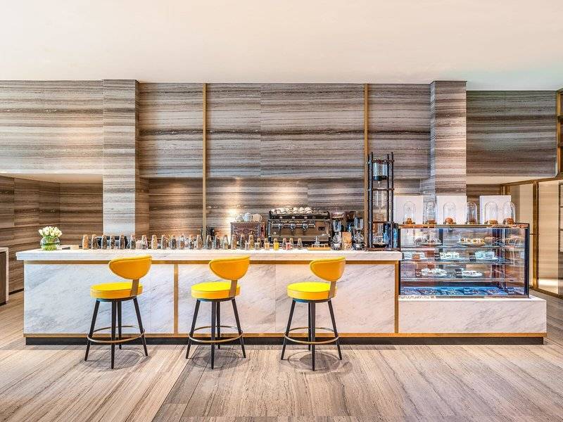 Barbereich im Rixos Gulf Hotel Doha mit Marmortheke und gelben Stühlen.