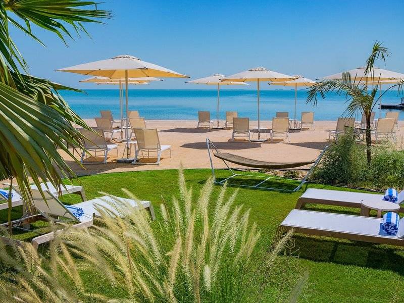 Strandbereich des Waldorf Astoria Doha Lusail Hotel mit Liegen und Sonnenschirmen