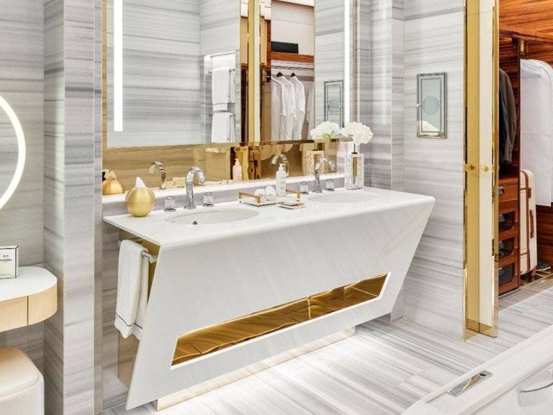 Luxuriöses Badezimmer im Fairmont Doha Hotel mit Marmorwänden, Doppelwaschbecken und Spiegeln.