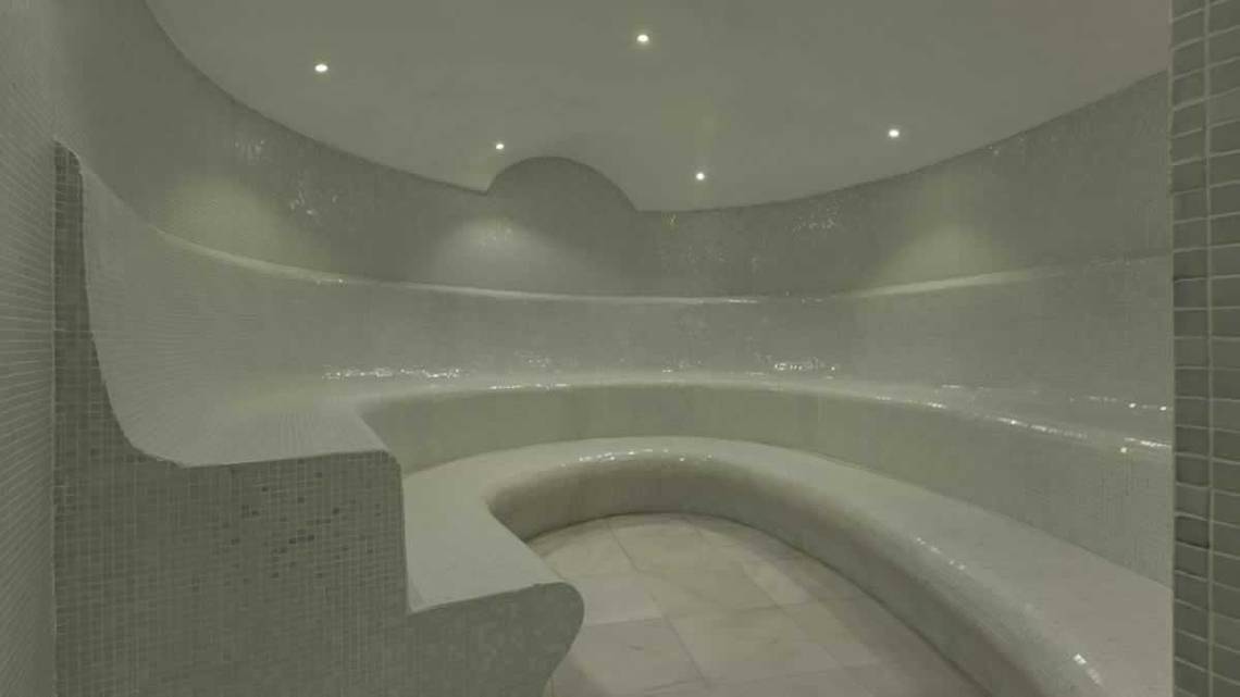 Innenansicht der Sauna im Royal Taj Mahal Hotel mit weißen Fliesen und gebogenen Bänken.