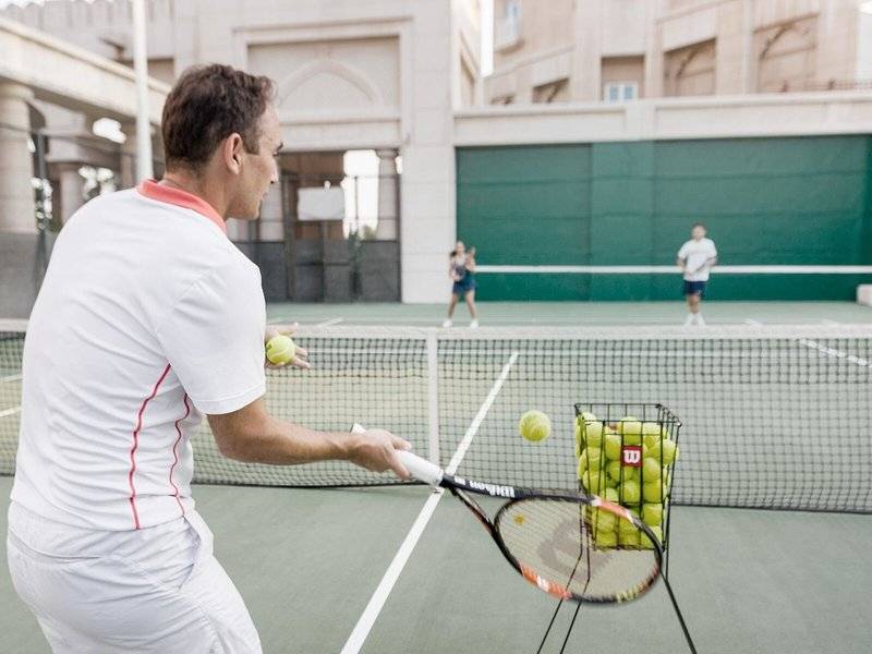 Tennisspieler im Four Seasons Hotel Doha schlägt einen Ball in Richtung Ballkorb.