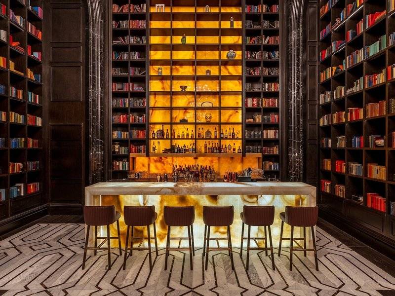 Bar in der Bibliothek des Raffles Doha mit Marmortheke und Bücherregalen.