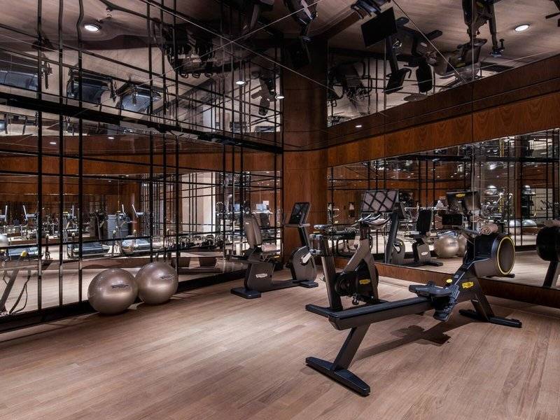 Fitnessstudio im Raffles Doha Hotel mit Glaswänden und moderner Trainingsausrüstung.