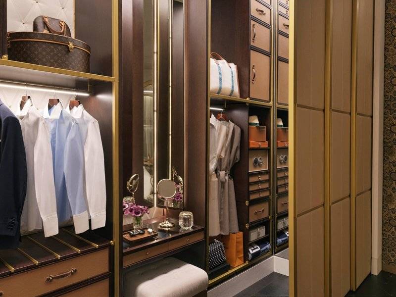 Ein geräumiger Kleiderschrank im Raffles Doha Hotel mit Spiegel, Regalen und Accessoires.