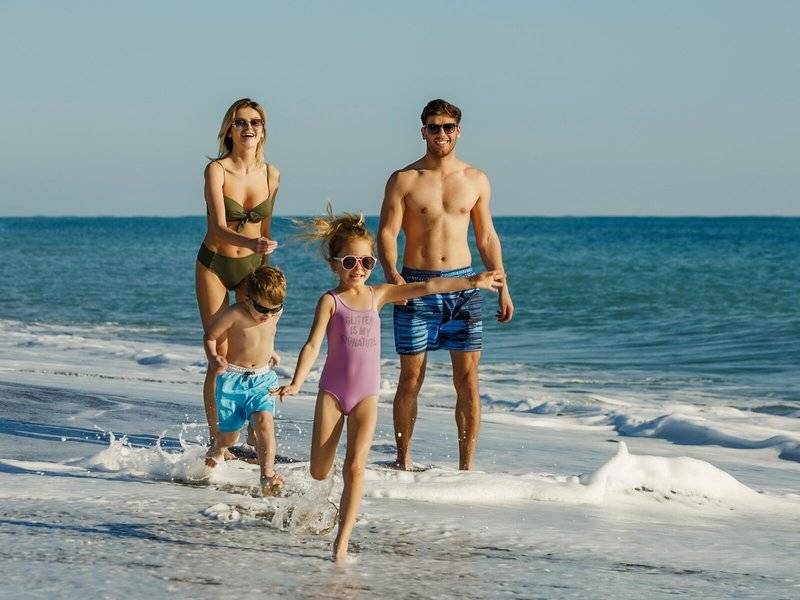 Familie am Strand vor dem Grand Park Lara Hotel, alle in Badekleidung und sonnigem Wetter