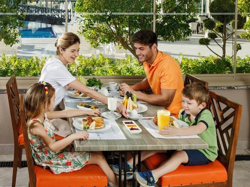 Familie am Frühstückstisch im Grand Park Lara Hotel mit Buffet und Orangensaft.