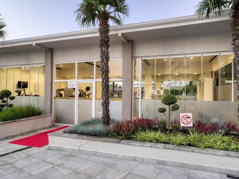 Außenansicht des Fitnesscenters des Grand Park Lara Hotels mit rotem Teppich und Palmen