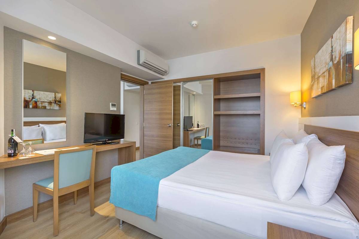 Innenansicht eines Hotelzimmers im Grand Park Lara mit Bett, Schreibtisch und Fernseher.