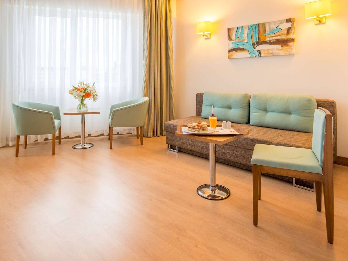 Hotelzimmer mit Sofa, Tisch, Blumen und Kissen.