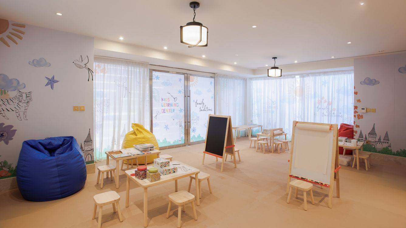 Kinderzimmer im St. Regis Doha mit bunten Wandmalereien, Tischen, Stühlen und einem Sitzsack.