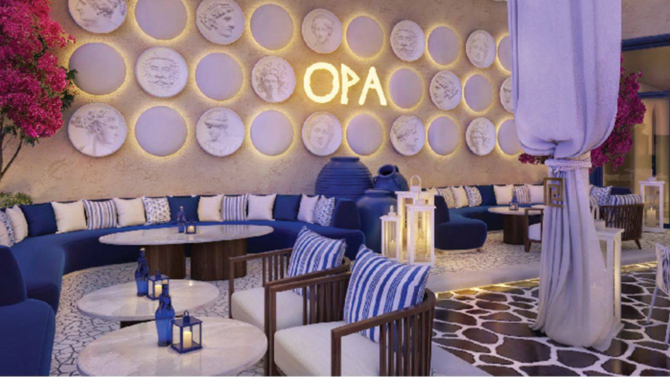 OPA Lounge im St. Regis Doha mit blauen Sofas, weißen Kissen und dekorativen Wandtellern.