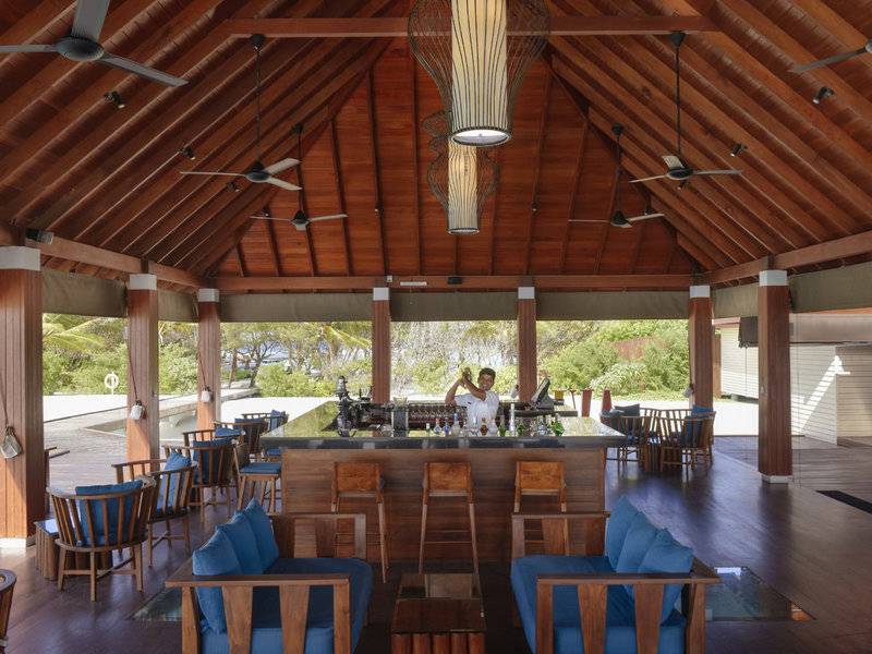 Innenansicht der Bar im Summer Island Maldives Hotel mit Holzmöbeln und Deckenventilatoren.
