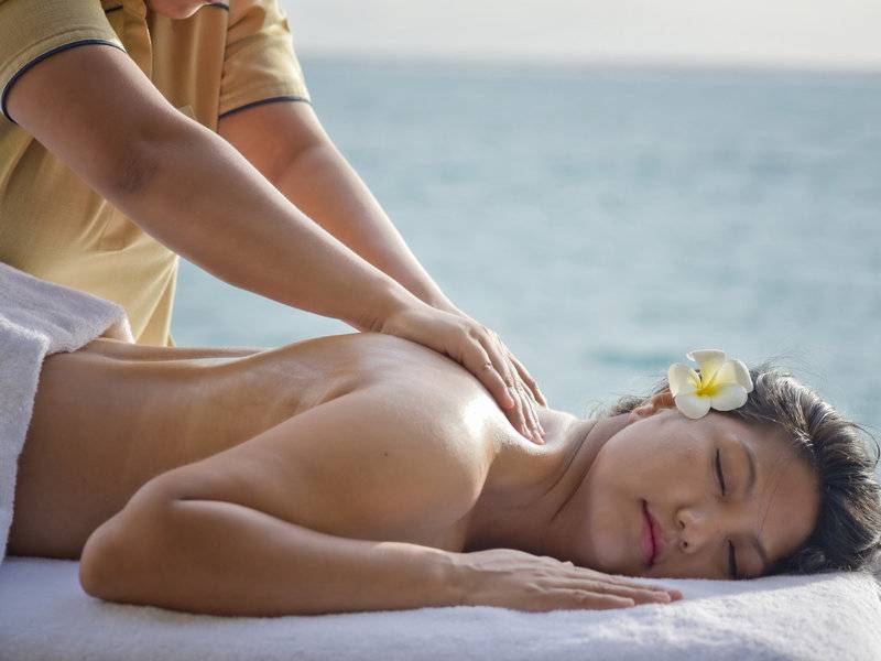 Eine Frau genießt eine Massage am Strand im Sommer Island Maldives Hotel.
