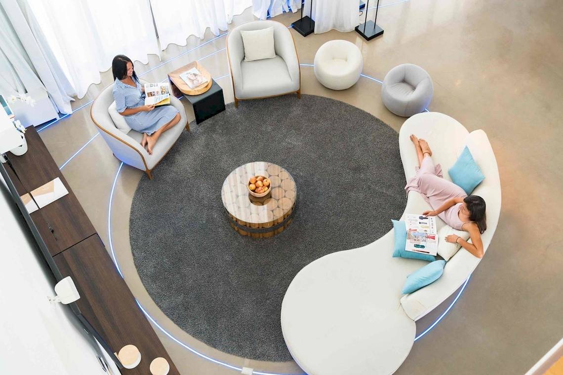 Zwei Frauen lesen in einer Lounge mit weißen Möbeln und einem Tisch mit Früchten im Nikki Beach Resort & Spa Dubai.