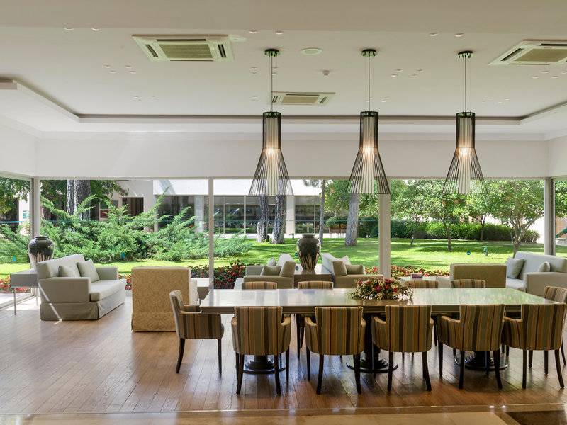 Innenansicht des Turquoise Hotels Essbereich mit großem Tisch, Stühlen und Blick auf Garten