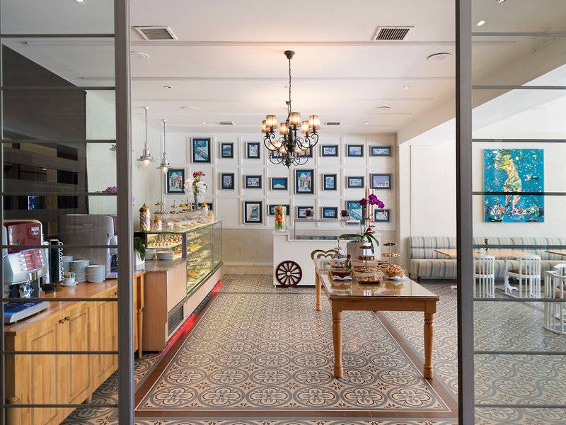 Innenansicht der Rezeption des Turquoise Hotels mit Möbeln, einem Tisch mit Dekoration und Gemälden an der Wand.