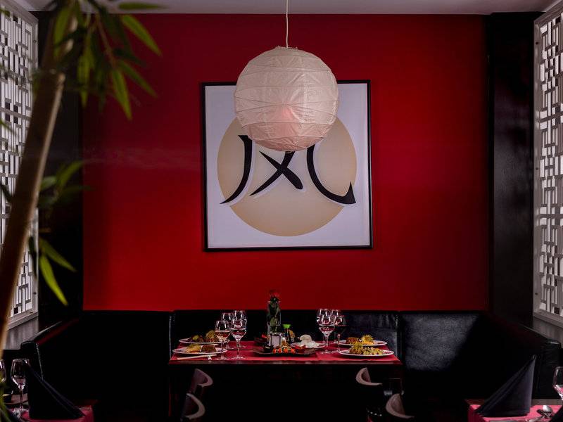 Inneneinrichtung des japanischen Restaurants im Turquoise Hotel mit rotem Hintergrund, hängendem Papierlaternen und Tisch mit Gerichten.