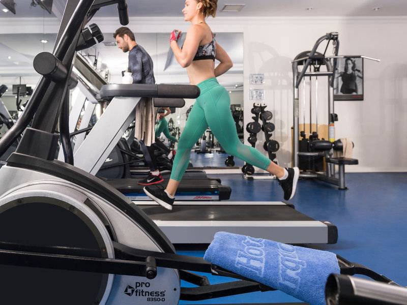 Fitnessstudio im Turquoise Hotel mit einer Frau, die auf einem Laufband läuft.