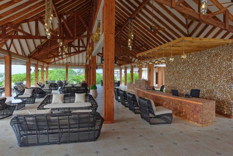 Loungebereich im Brennia Kottefaru Maldives Hotel mit Holzmöbeln und Deckenleuchten.