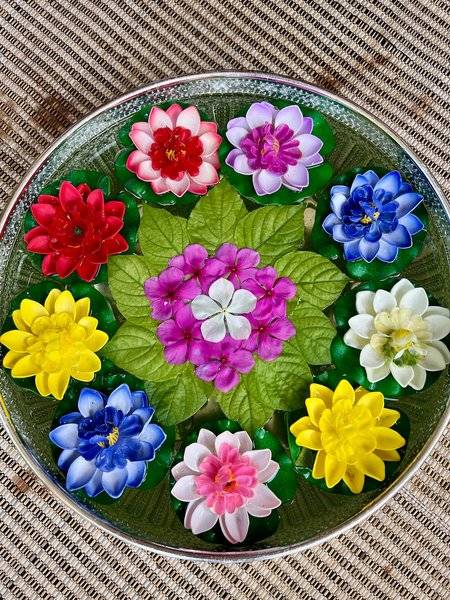 Eine Schale mit bunten künstlichen Blumen auf einer gewebten Matte.