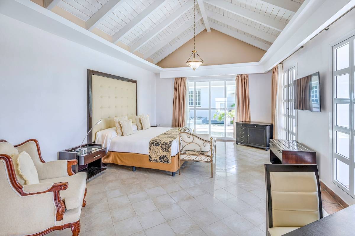 Luxuriöses Schlafzimmer im Paradisus Varadero Resort & Spa mit Kingsize-Bett, Holzmöbeln und großen Fenstern.