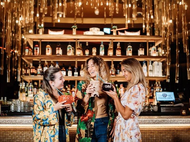 Drei Frauen, die Cocktails in der Bar des Hilton Dubai Palm Jumeirah halten.