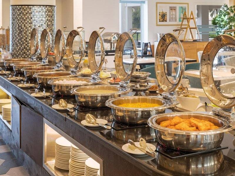 Buffettisch im Sealine Beach, A Murwab Resort mit verschiedenen Speisen in Silberschalen.
