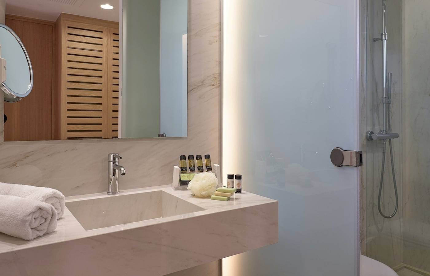 Badezimmer im Pilot Beach Resort mit Marmorwaschbecken, Spiegel und Duschkabine.