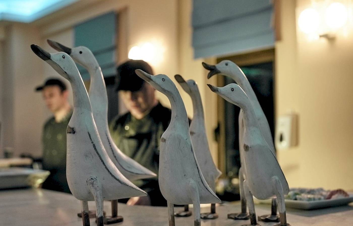 Sechs weiße Enten-Skulpturen auf einem Tisch im Pilot Beach Resort.