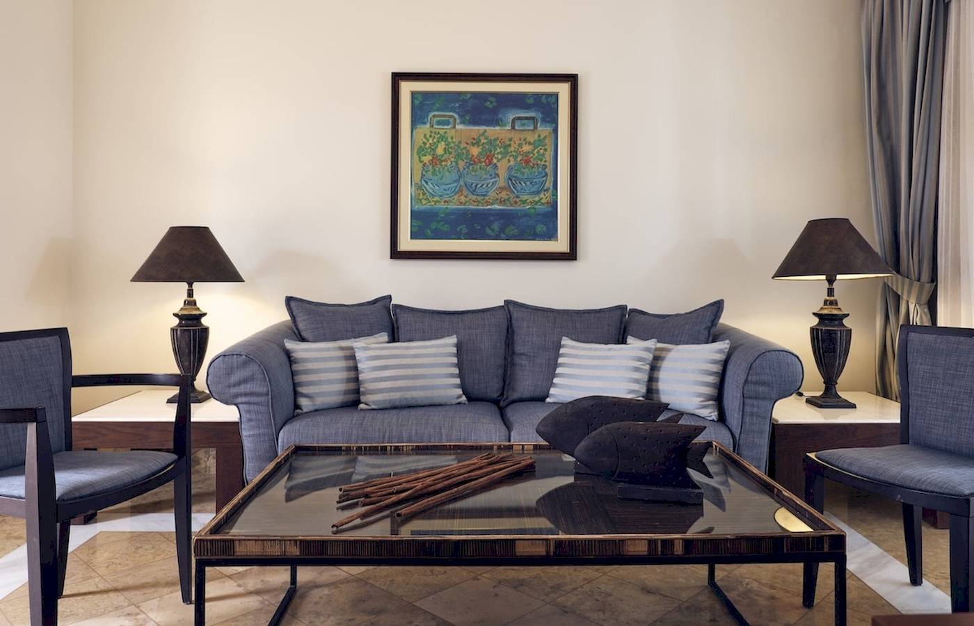 Wohnzimmer des Pilot Beach Resorts mit grauem Sofa, blauer Wand und Gemälde