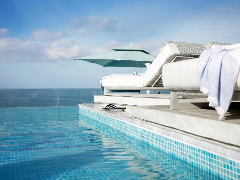 Außenpool des Mare Paphos Hotels mit Lounge-Sesseln und Blick aufs Meer.