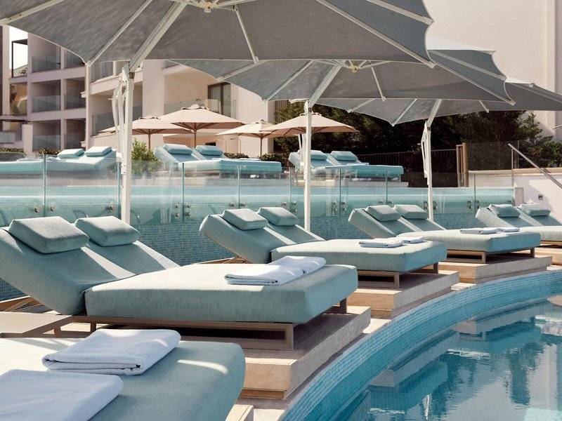 Poolseite des Mare Paphos Hotels mit Loungestühlen und Sonnenschirmen.