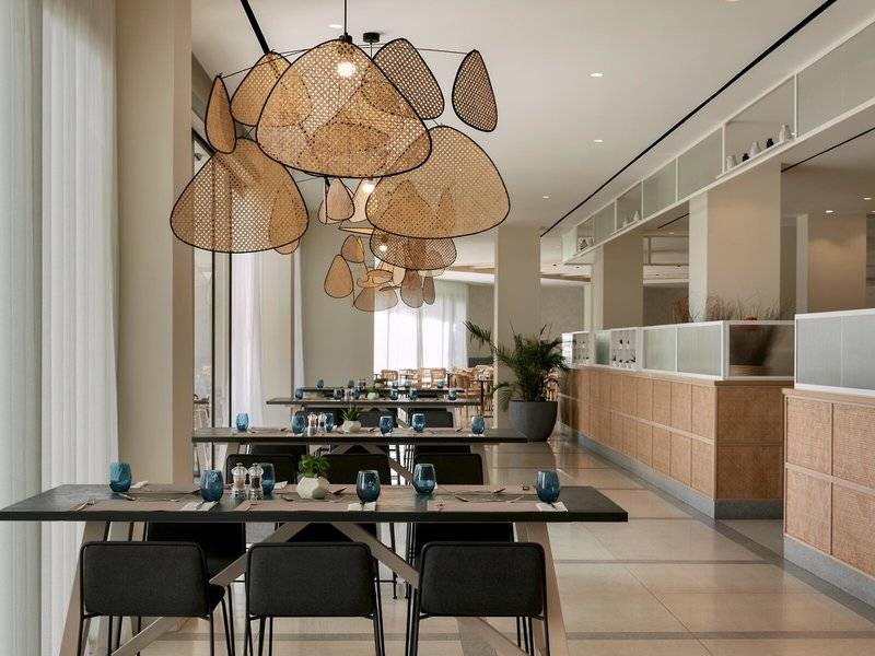 Ein modernes Restaurant im Mare Paphos Hotel mit Tischbeleuchtung und grünen Pflanzen.