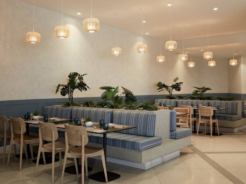 Innenbereich des Mare Paphos Hotels mit Sitzgelegenheiten, Tischen, Pflanzen und dekorativen Lampen.